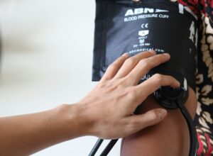 Blood pressure cuff on a male arm and a hand holding it.