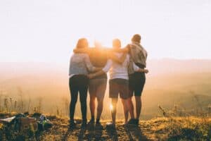 Four teenagers arm in arm looking out to the sunset