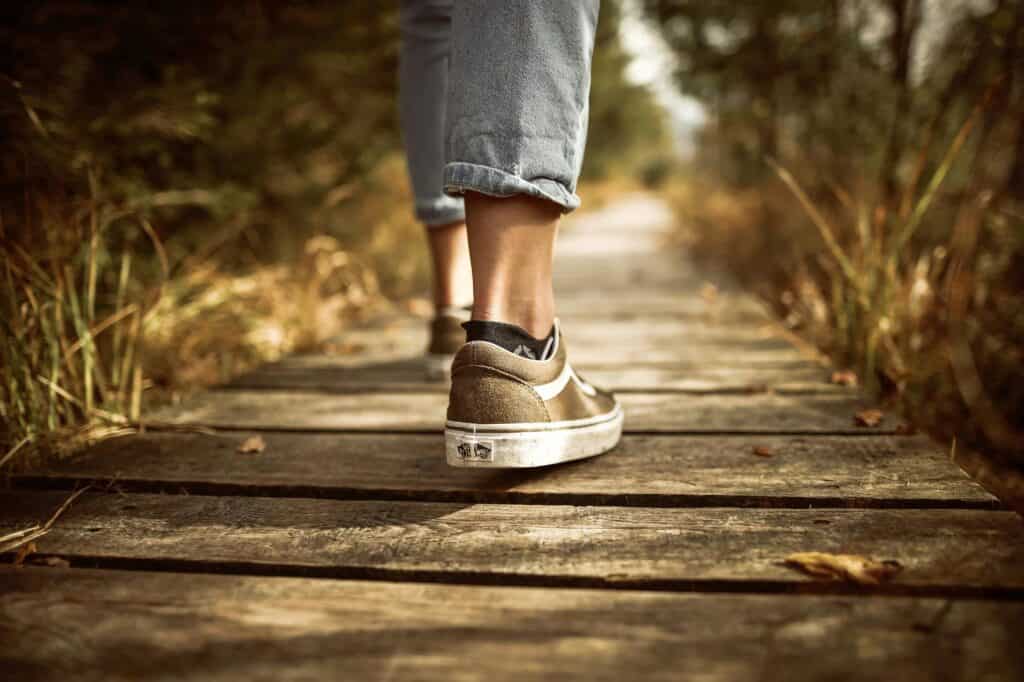 two feet walking over a wooden bridge in the forest