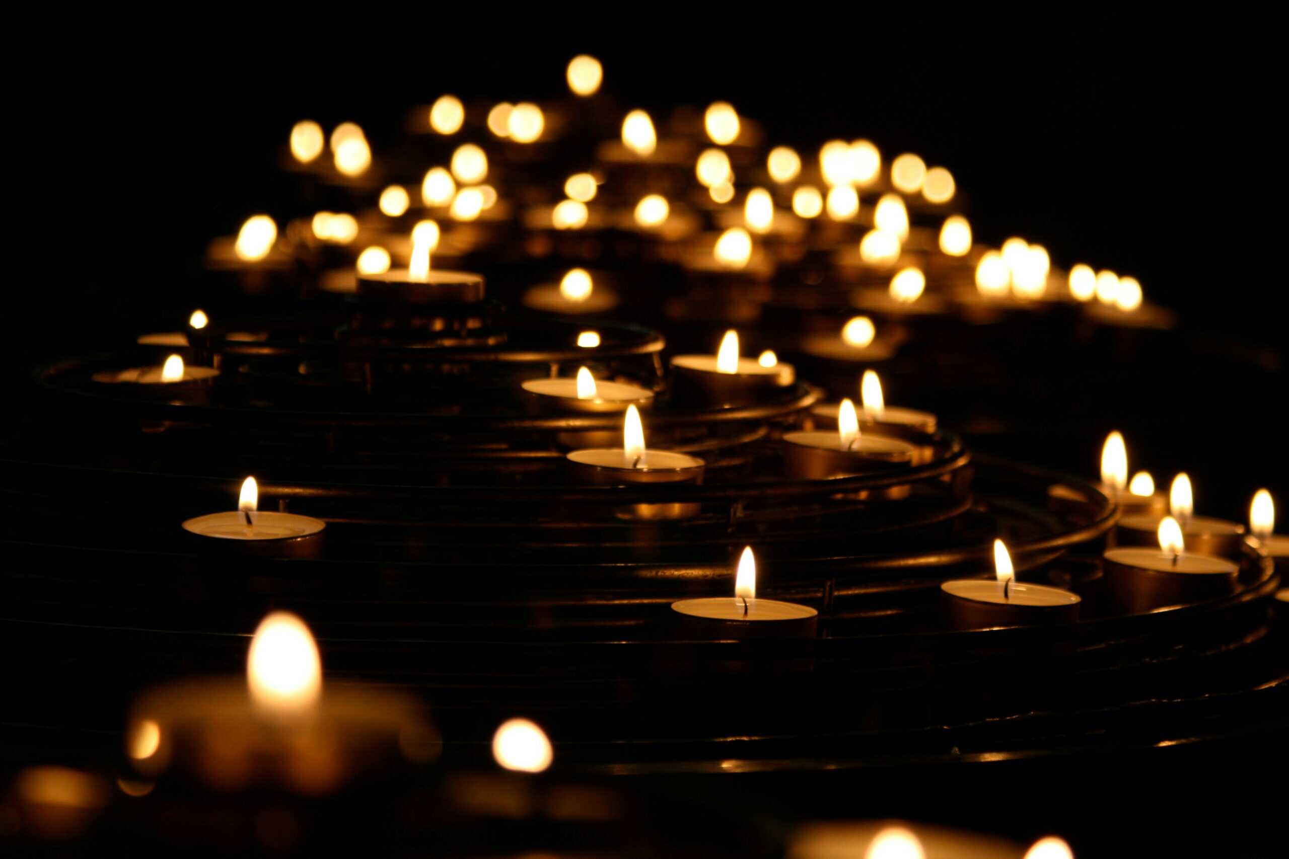 A number of tea lights on the floor in the dark with the candles lighting up