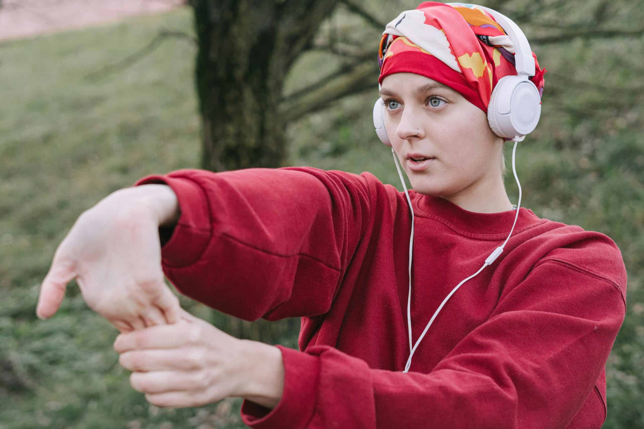woman who has had chemotherapy for cancer wearing a headscarf and is stretching ready to exercise
